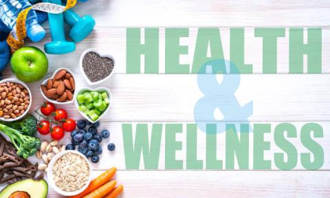 Various healthy foods in bowls and other items such as weights. Health and Wellness text is on the right-hand side