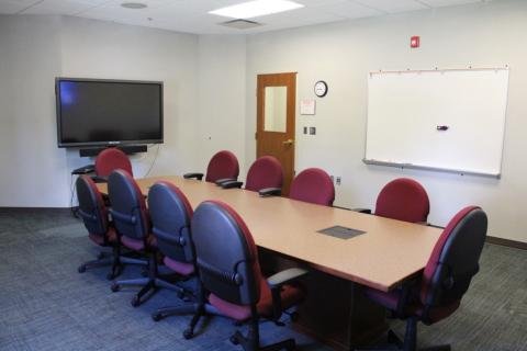 Picture of Meeting Room B with a table and chairs. Smart Board also in shot. 