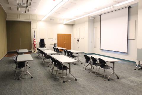 Picture of Meeting Room C1 with the divider up and tables and chairs.